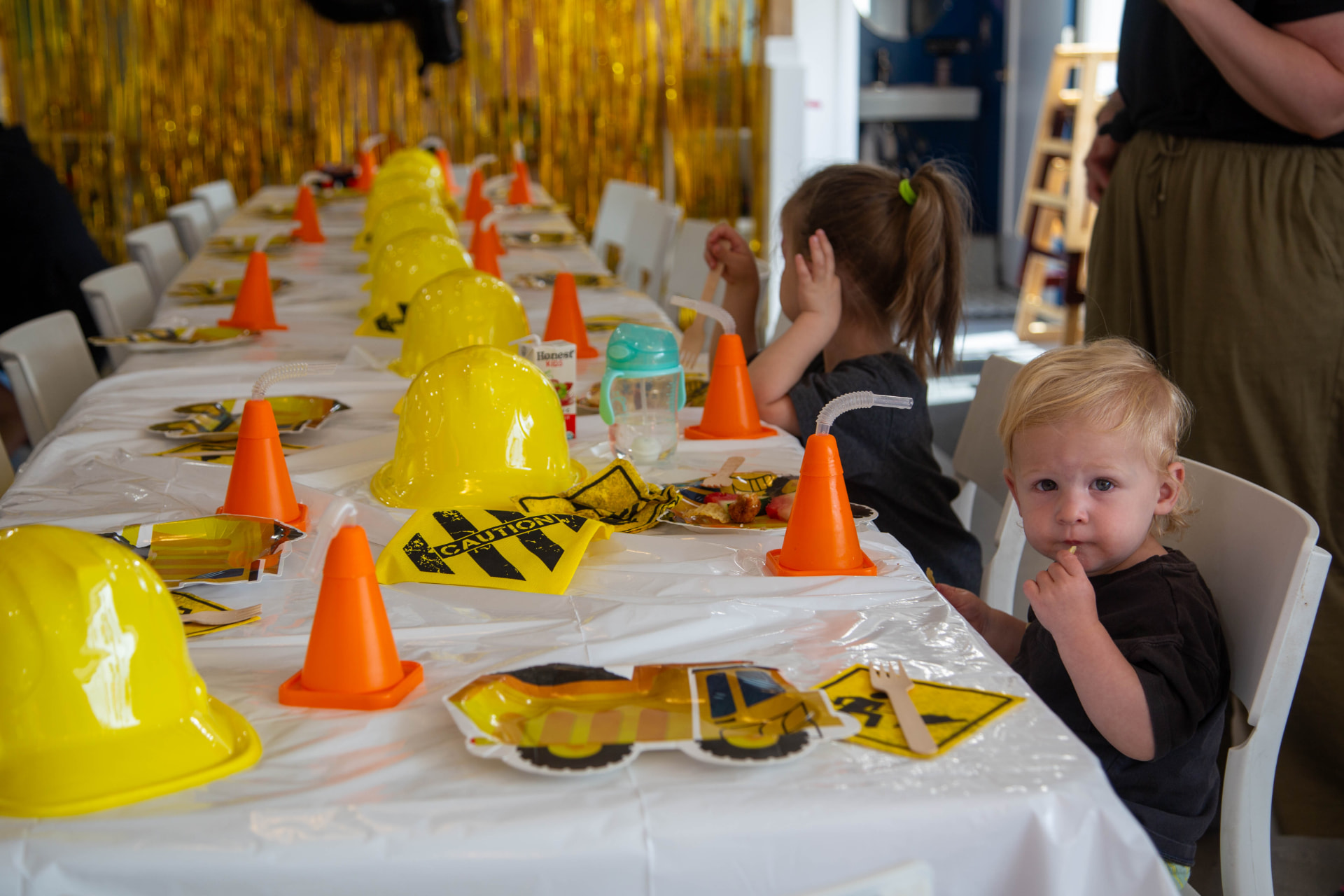 Children enjoying a construction-themed birthday table with yellow hard hats and traffic cone decorations at tumble HAUS