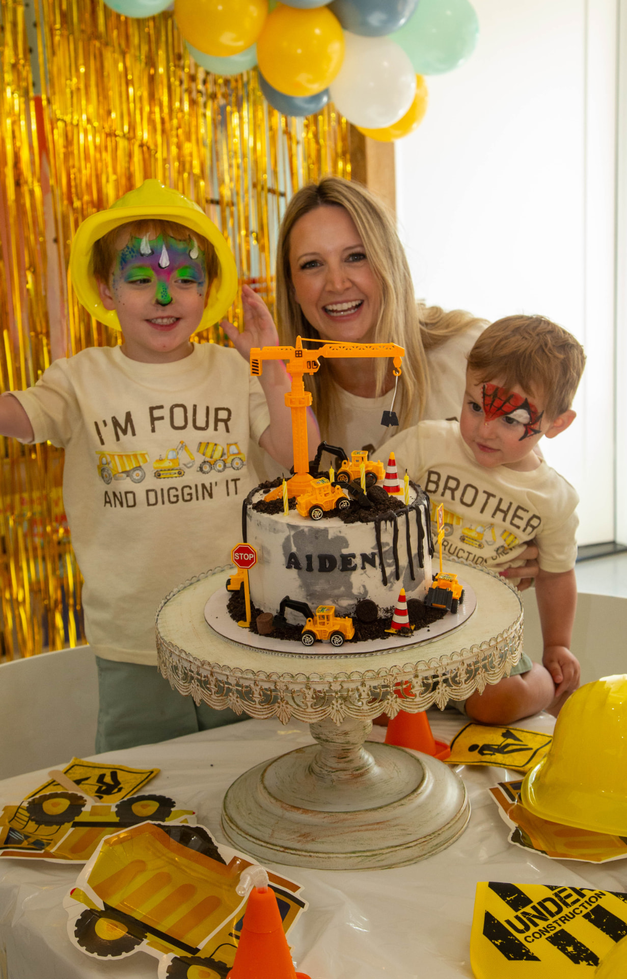 Caregiver and two children celebrating around a custom construction birthday cake at tumble HAUS