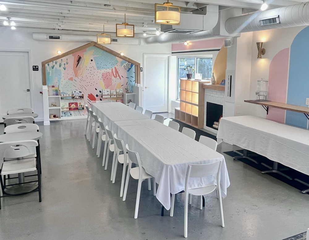 tumble HAUS party space set with long white-linen tables, folding chairs and pastel wall murals