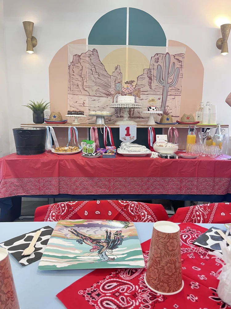 Above & Beyond dessert table at tumble HAUS with a desert backdrop, cake stand and cowboy theme decor