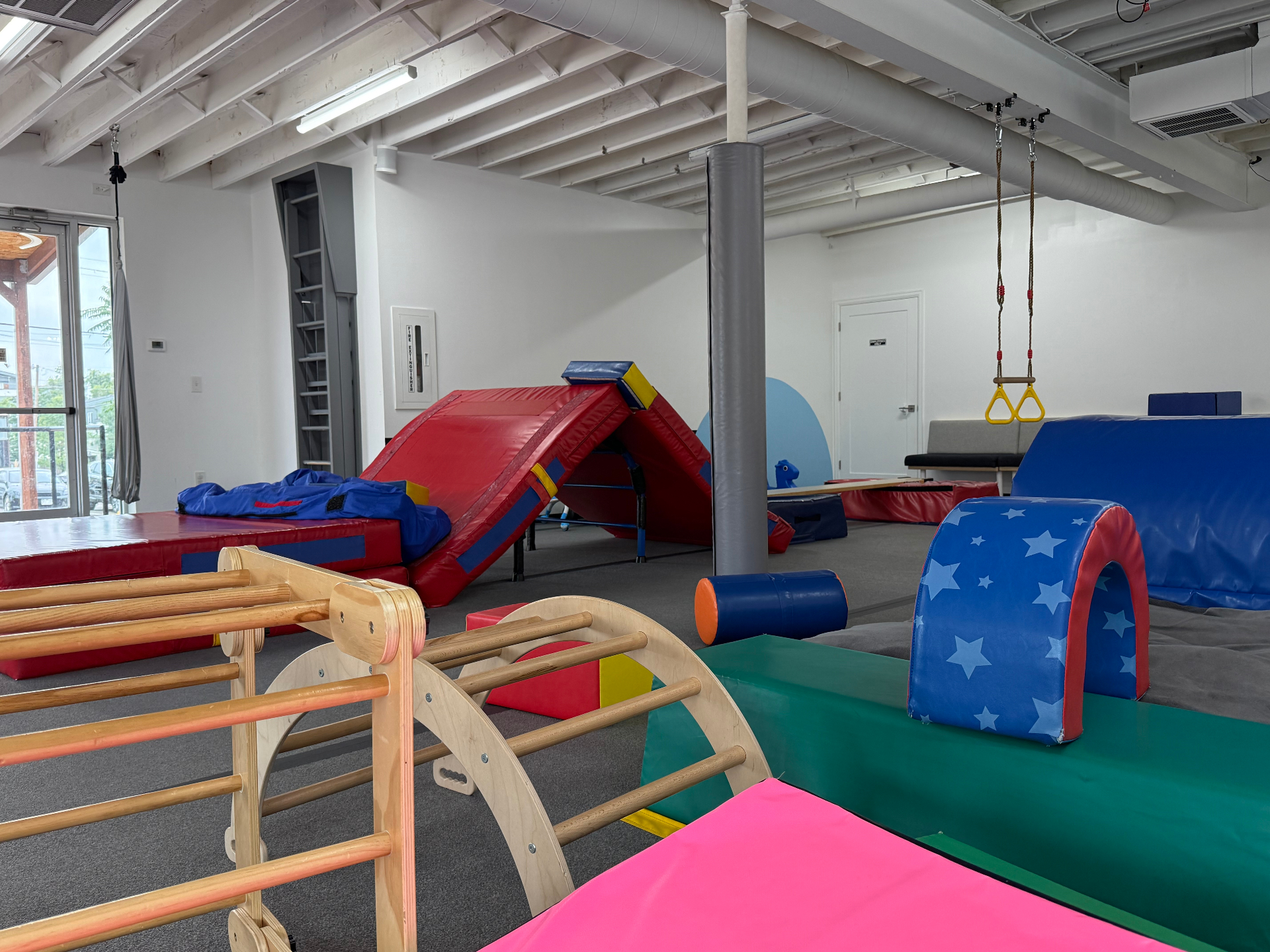 Indoor play gym at tumble HAUS Denver with foam ramps, hanging rings and toddler climbing equipment