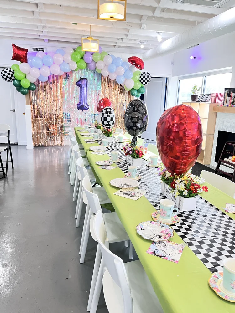 Whimsical mushroom and checkerboard themed birthday party table at tumble HAUS Denver with a pastel balloon arch