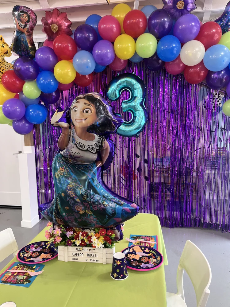 Encanto themed 3rd birthday at tumble HAUS with a colorful rainbow balloon arch and purple fringe backdrop