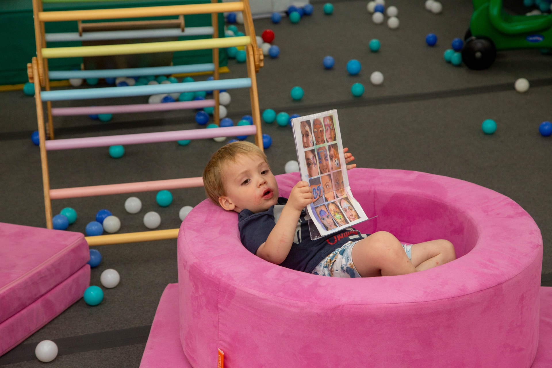 Young guest relaxing in the soft play area while choosing a face-painting design
