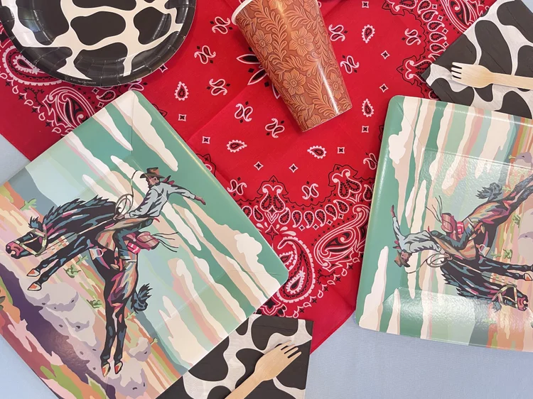 Cowboy party place settings at tumble HAUS with rodeo plates, cow-print napkins and red bandanas