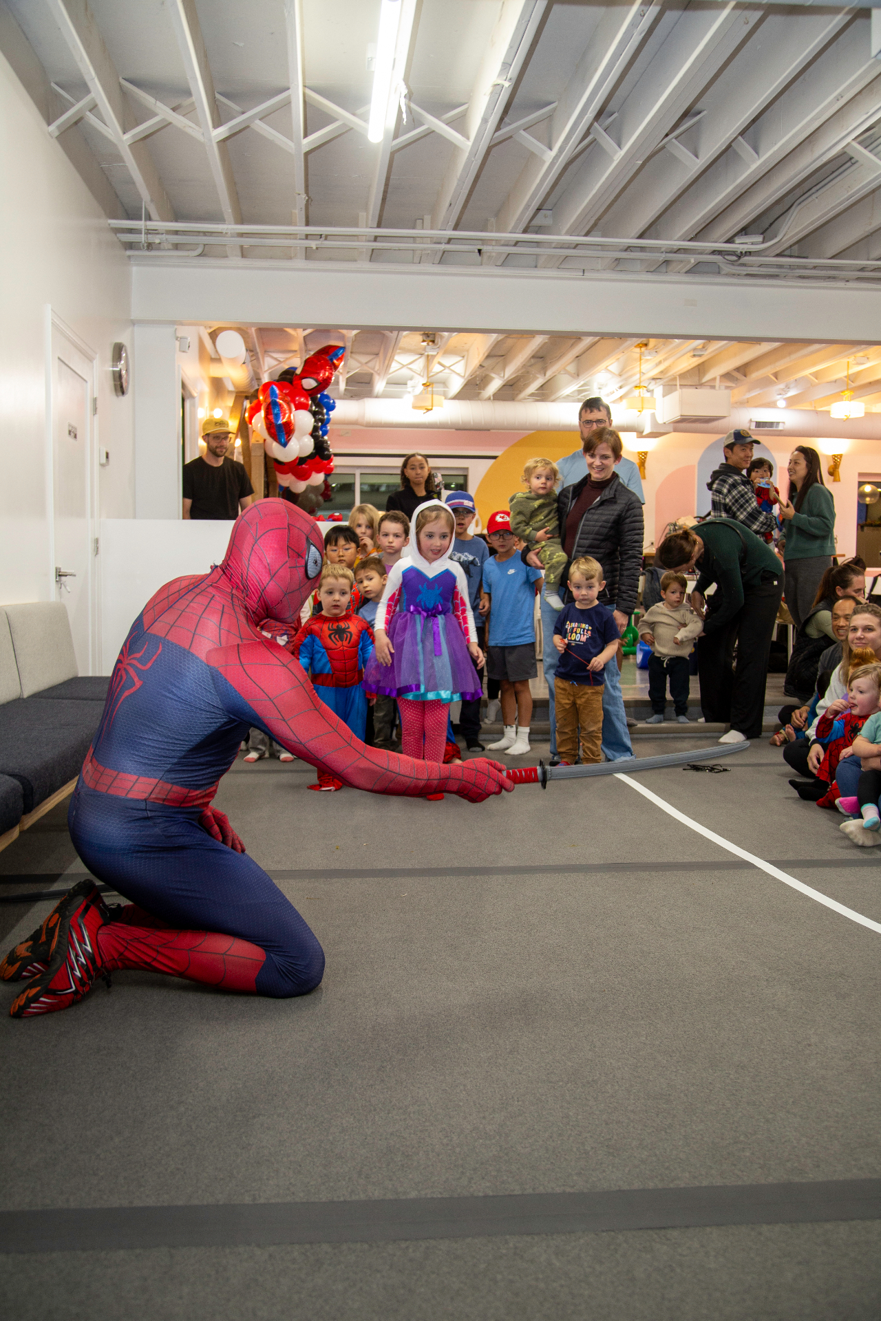 Spider-Man performing for a crowd of children and parents at tumble HAUS Denver