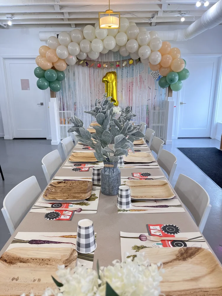Rustic farm themed first birthday at tumble HAUS with a neutral balloon arch, greenery and tractor place settings