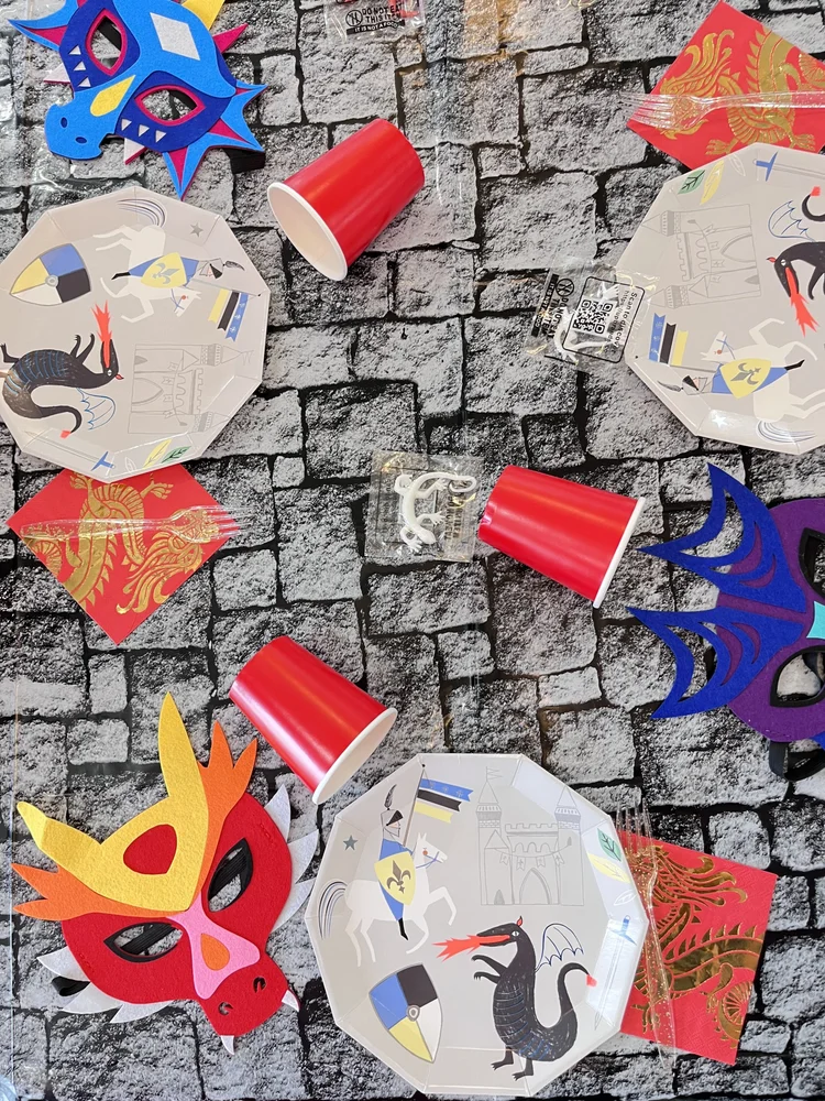 Medieval dragon party place settings at tumble HAUS with knight plates, felt dragon masks and a stone backdrop