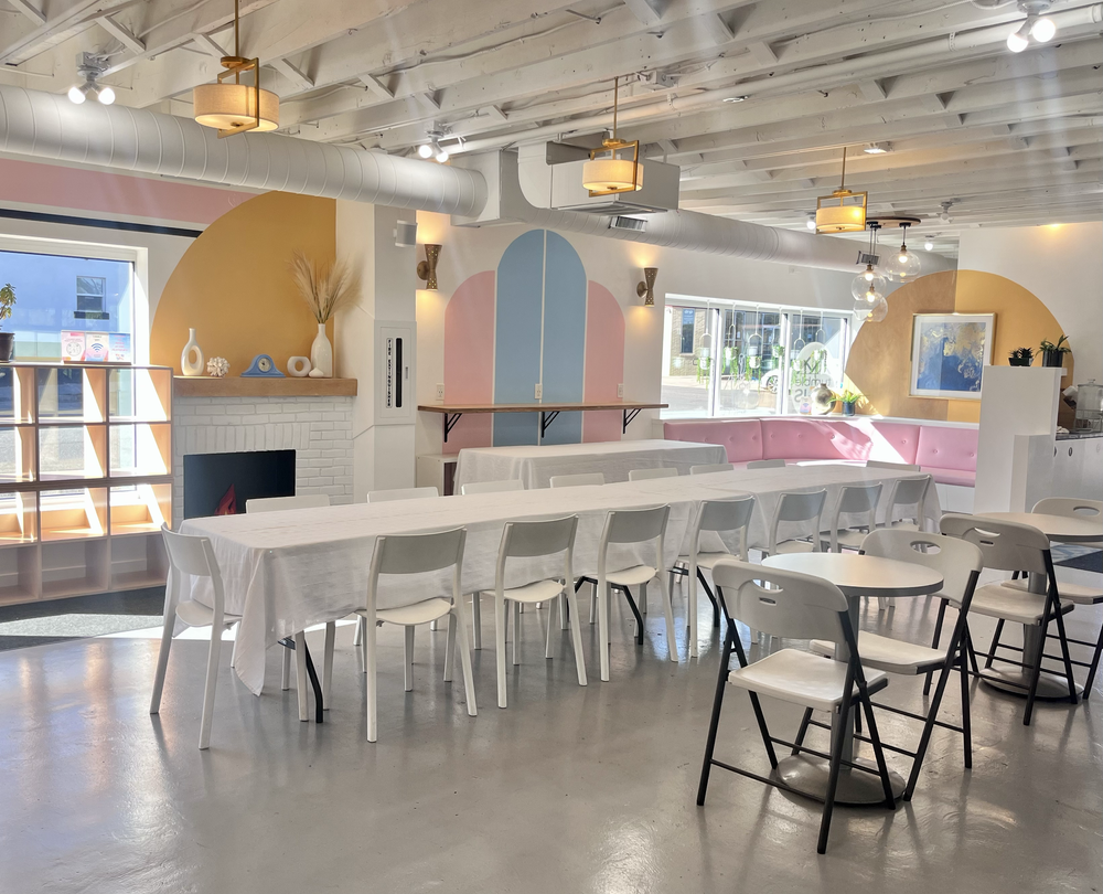 Open event space at tumble HAUS with pastel arches, white tables, pink banquette seating and a fireplace