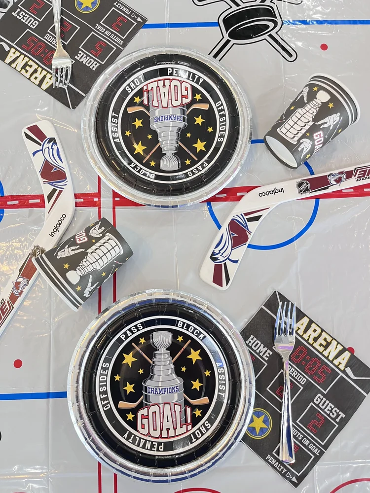 Hockey themed birthday party place settings at tumble HAUS with rink table cover, sticks and championship plates