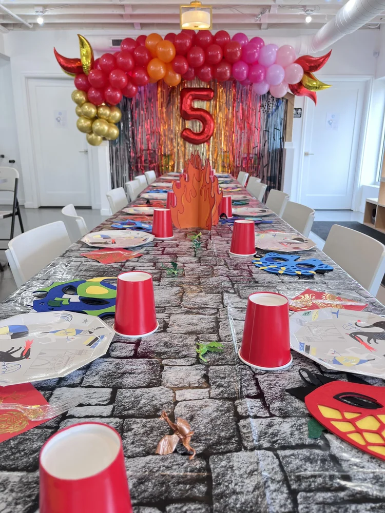 Dragon themed birthday party table at tumble HAUS with red cups, flame centerpiece and warrior masks