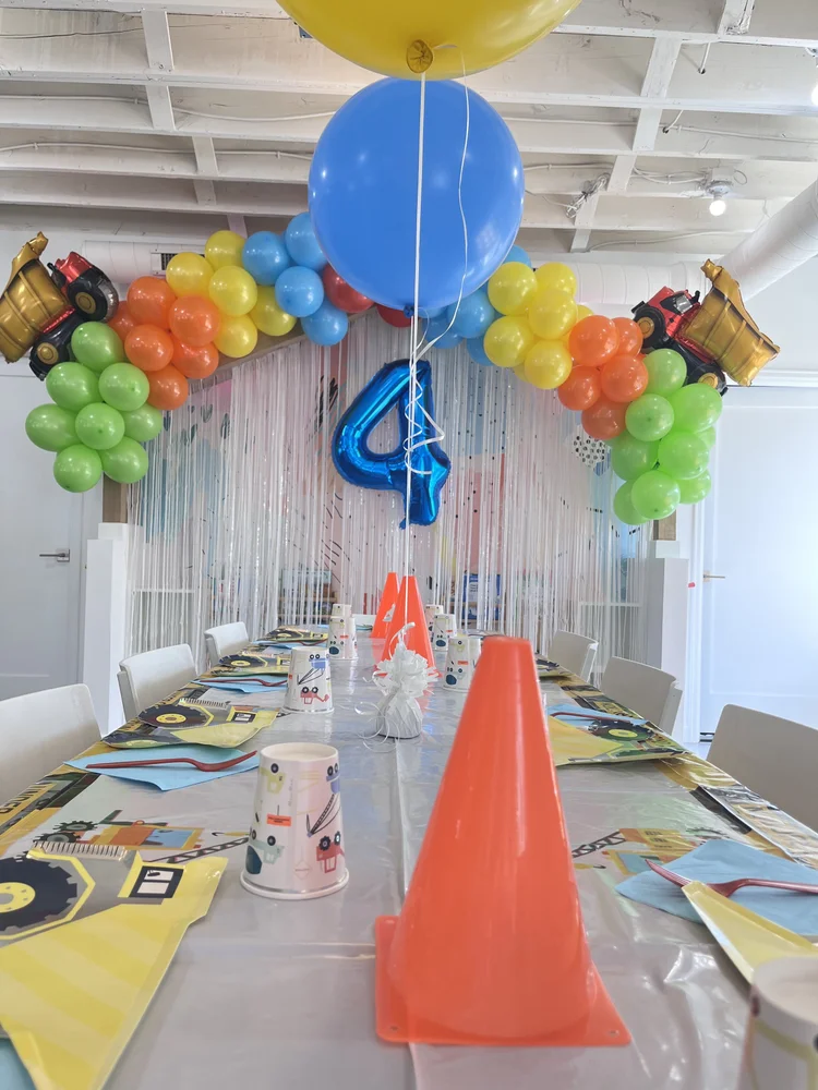 Construction-themed birthday party at tumble HAUS with dump truck balloons, traffic cones and a number 4 balloon