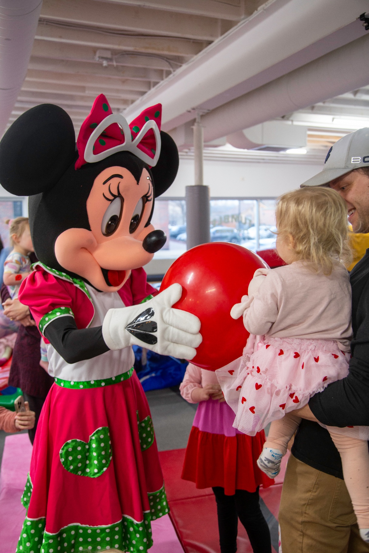Minnie Mouse handing a balloon to a child at tumble HAUS in Denver