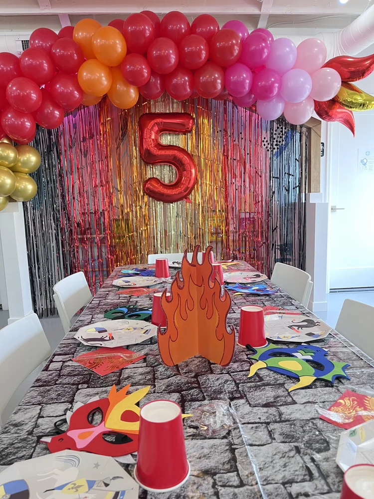 Dragon and knights 5th birthday party at tumble HAUS with a fiery balloon arch and cobblestone table runner
